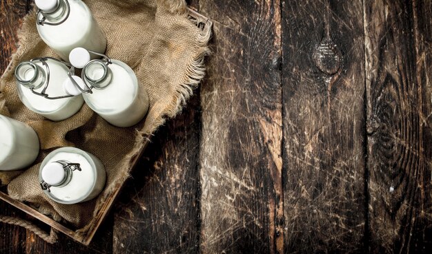 Bouteilles de lait frais dans une boîte. Sur un fond en bois.