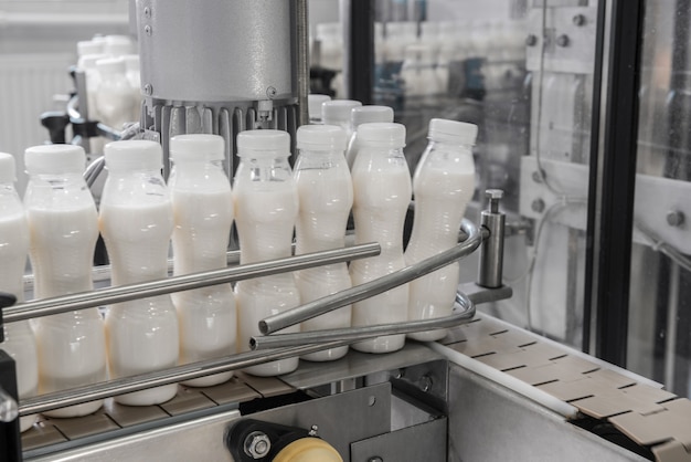 Bouteilles de lait en plastique sur tapis roulant. équipement à l'usine laitière