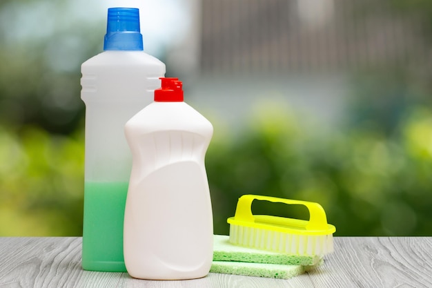 Bouteilles de liquide vaisselle et brosse sur fond vert