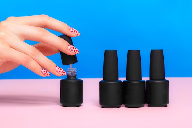 Bouteilles noires de vernis à ongles sur un fond coloré Conception de manucure