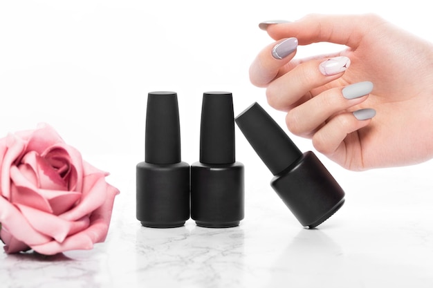 Bouteilles noires de vernis à ongles sur fond de fleurs Conception de manucure