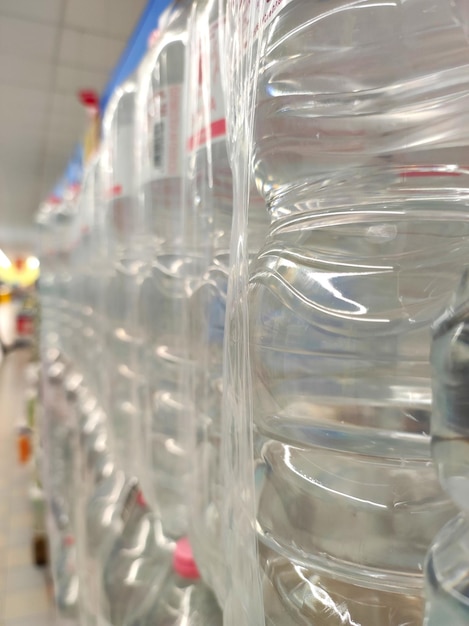 Bouteilles en plastique emballées avec de l'eau naturelle empilées en rangées une par une dans un supermarché