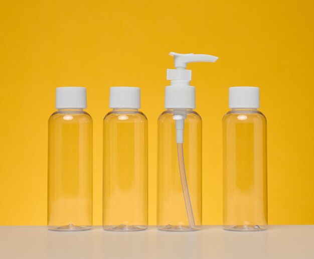 Bouteilles en plastique transparentes pour cosmétiques liquides sur fond jaune