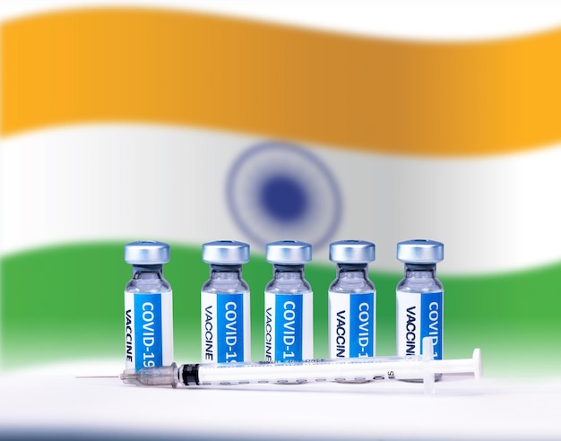 Bouteilles et seringue de vaccin contre le virus corona Covid 19 avec un fond de drapeau national de l'INDE