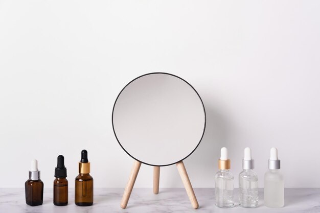 Bouteilles de sérum ou de collagène liquide et miroir sur table en marbre Concept de produits cosmétiques de beauté anti-âge