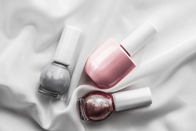 Bouteilles de vernis à ongles sur fond de soie produits de manucure français et cosmétiques de maquillage de vernis à ongles pour la marque de beauté de luxe et la conception d'art flatlay de vacances