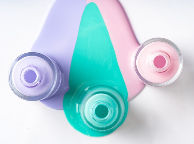 Photo bouteilles de vernis à ongles renversées de couleur pastel sur blanc