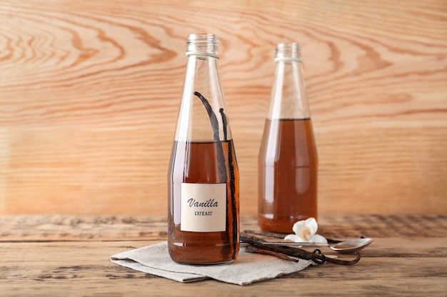 Bouteilles en verre avec extrait de vanille sur table en bois