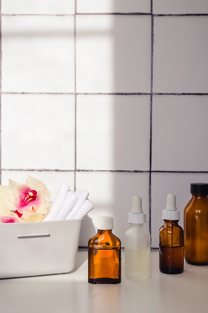 Bouteilles en verre avec pipettes et récipient en plastique avec serviettes sur fond de carreaux blancs et noirs