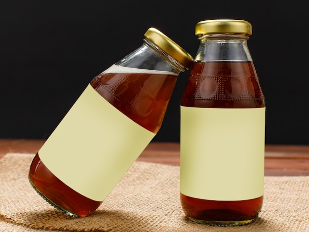 Photo bouteilles en verre publicitaires de délicieuses boissons biologiques pour un extrait de rafraîchissement santé à partir d'herbes naturelles et de fruits de ginkgo, de longane et de noix de malva. boissons et ingrédients servis sur plateau de cuisine.