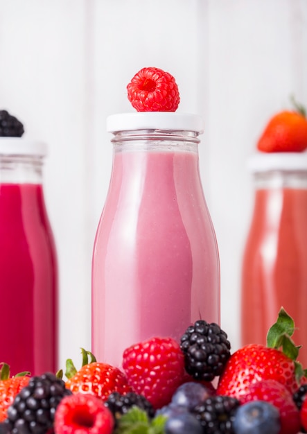 Bouteilles en verre avec smoothie de fruits frais d'été sur table en bois. Framboises et framboises aux bleuets et mûres.