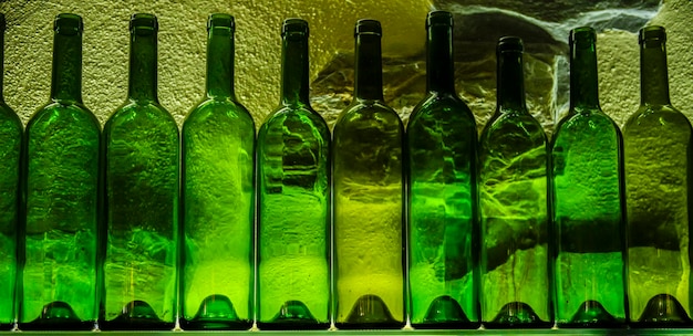 Bouteilles en verre vertes vides sur une étagère