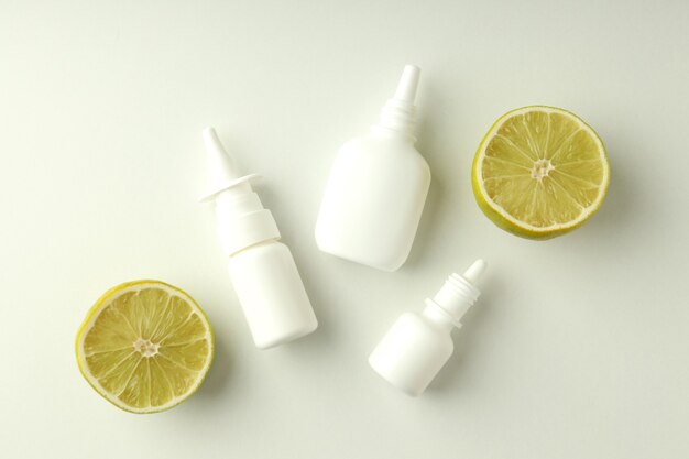 Bouteilles vierges de spray nasal et moitiés de citron vert sur fond blanc