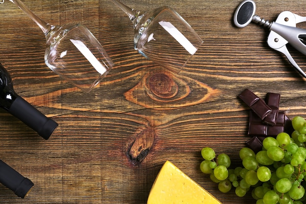 Bouteilles de vin rouge et blanc, raisin, fromage et verres sur table en bois. Vue de dessus avec espace de copie. Nature morte. Mise à plat