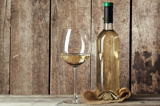 Photo bouteilles de vin avec verre, mur en bois