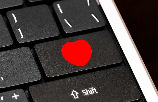 Bouton coeur rouge sur le clavier de l'ordinateur. Concept de rencontres sur Internet.