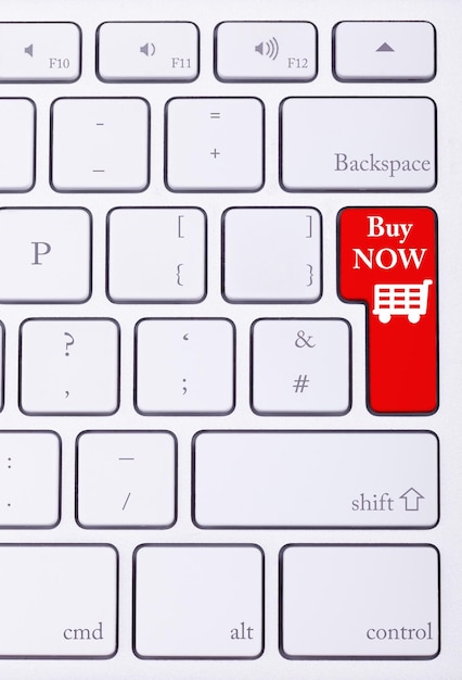 Bouton rouge sur le clavier avec acheter maintenant des mots dessus et un panier. E-commerce et vente en ligne