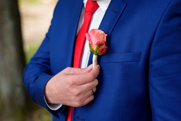 Une boutonnière tient le costume de fiancé une main