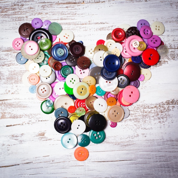 Boutons colorés en forme de coeur sur la table en bois vintage