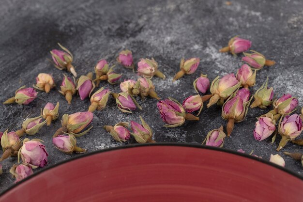 Boutons de rose séchés placés sur un fond de pierre.