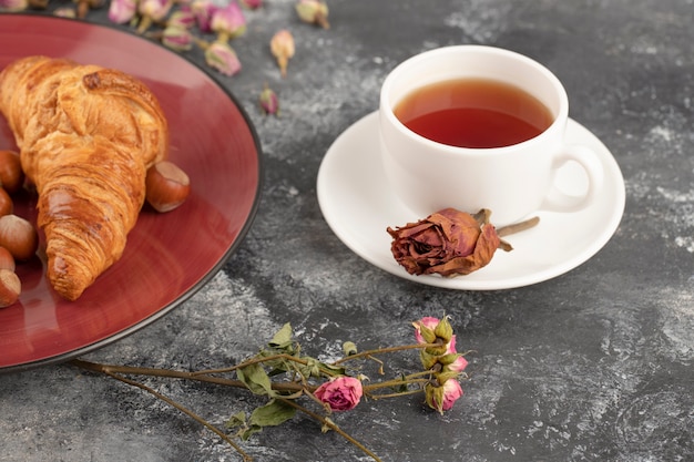 Boutons de rose séchés avec une tasse de thé chaud posé sur une table en pierre.