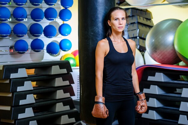 Boxe de belle femme sportive avec sac de boxe rouge au gymnase