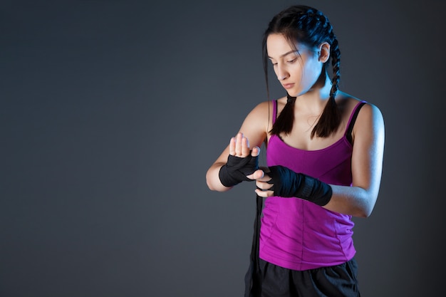 Boxer femelle enveloppe ses mains avec des wraps de boxe noirs