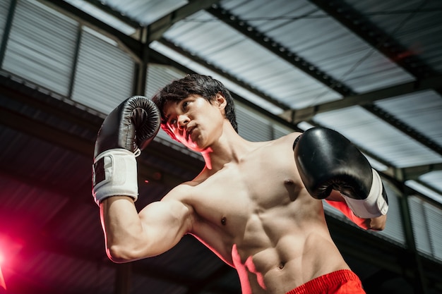 Boxer en gants de boxe avec swing punch contre l'arène du ring