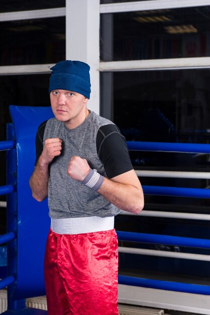 Boxeur athlétique debout dans une pose serrant ses poings dans un ring de boxe régulier