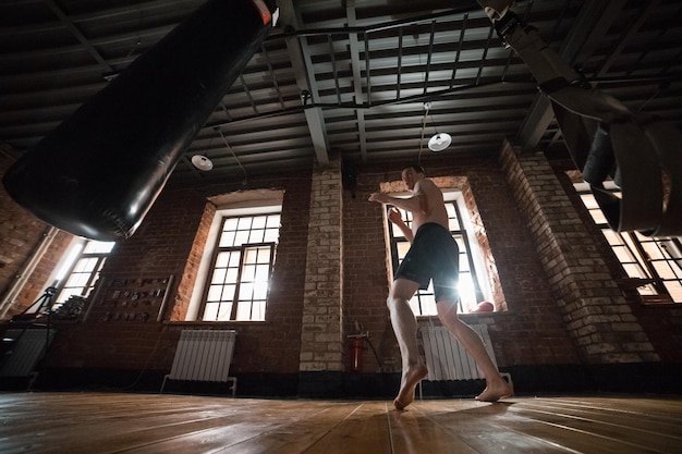 Un boxeur athlétique s'entraînant avec un sac de boxe dans la salle de sport