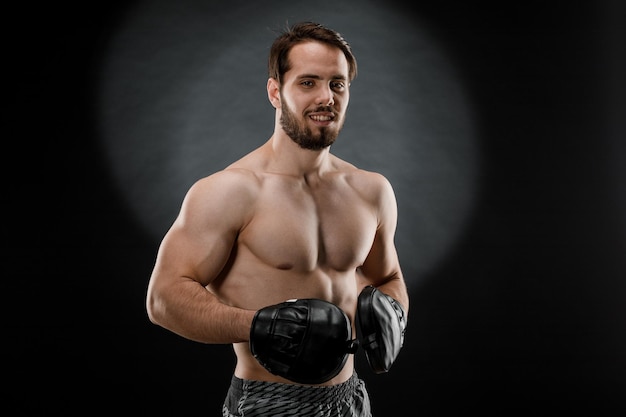 Le boxeur est un combattant regardant avec colère la caméra Jeune modèle de fitness masculin caucasien isolé sur fond noir