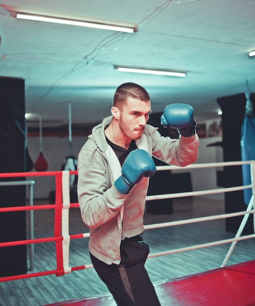 Boxeur de gars de sport boxe dans le ring au gymnase. processus de formation d'un boxeur