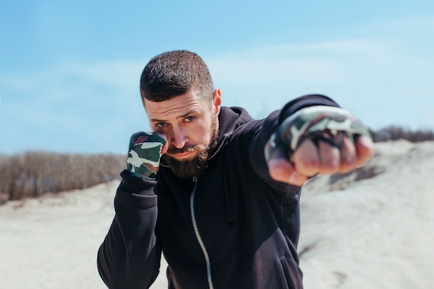 Un boxeur gonflé s'entraîne sur le poing de sable au premier plan