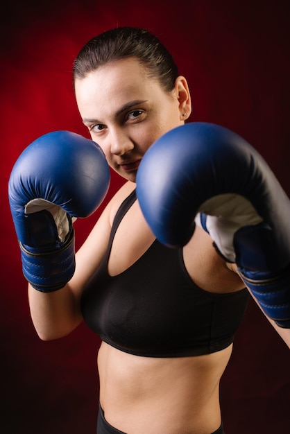 Boxeur de sport extrême portant des gants de boxe bleus sur fond rouge foncé