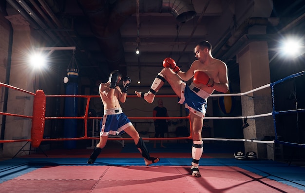 Les boxeurs s'entraînent au kickboxing sur le ring au club de santé