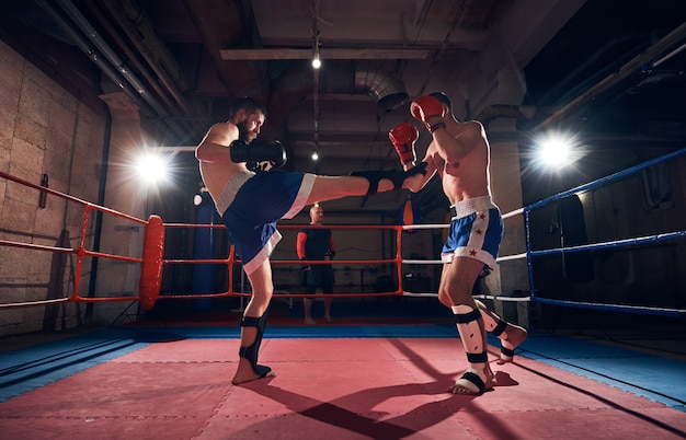 Les boxeurs s'entraînent au kickboxing sur le ring au club de santé