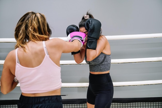 Boxeuse frappant son adversaire pendant qu'elle se couvre dans un entraînement sur le ring