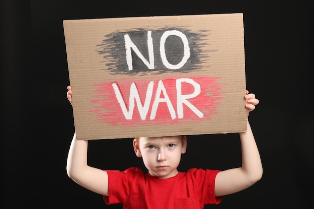 Boy holding poster Pas de guerre sur fond noir