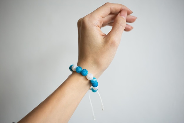 Bracelet avec pierres naturelles de différentes couleurs sur une belle main d'une jeune fille sur fond blanc