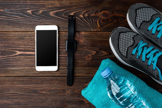 Bracelet de remise en forme, baskets et téléphone mobile sur bois foncé