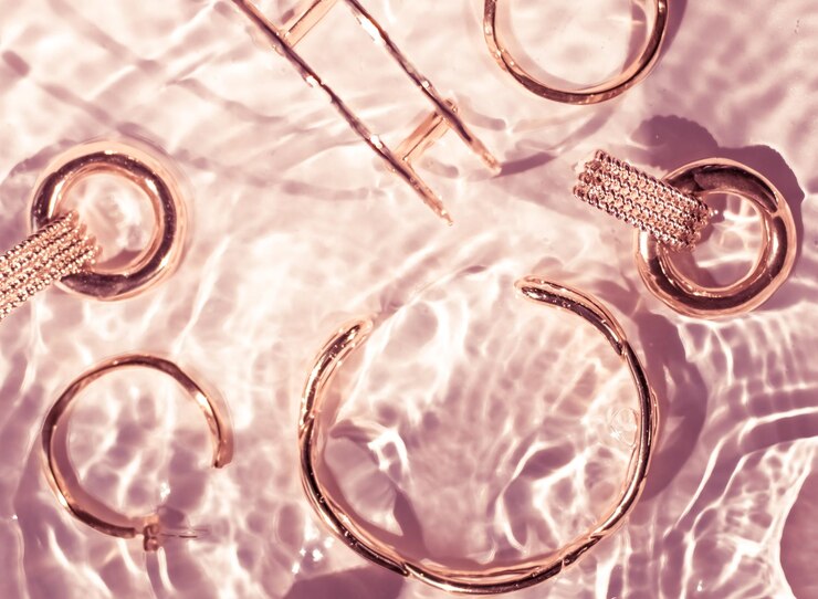 Bracelets en or rose boucles d'oreilles bagues bijoux sur fond d'eau rose glamour de luxe et conception de beauté de vacances pour les annonces de marque de bijoux