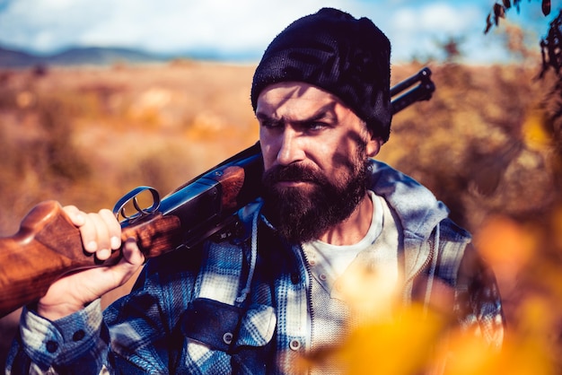 Braconnier dans la forêt. Chasseur barbu tenant un pistolet et marchant dans la forêt. Permis de chasse. Chasseur avec fusil de chasse à la chasse.