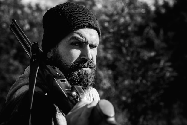 Braconnier dans la forêt Chasseur avec fusil de chasse à la chasse Autunm chasse Saison de chasse fermée et ouverte Chasseur barbu tenant un fusil et marchant dans la forêt