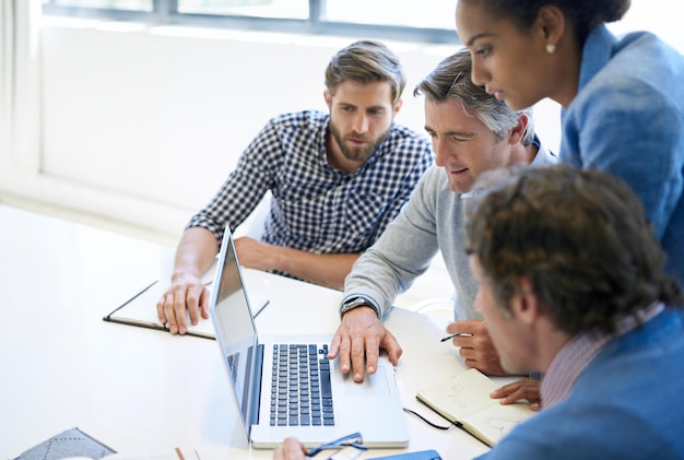 Le brainstorming est meilleur avec la technologie Un groupe de collègues de travail discutant du travail sur un ordinateur portable lors d'une réunion dans la salle de conférence