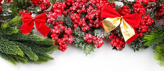 Branche d'arbre de Noël avec des baies rouges et des arcs sur une surface blanche