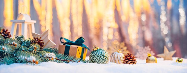 Branche d'arbre de Noël avec un cadeau et des décorations dans la neige au soleil