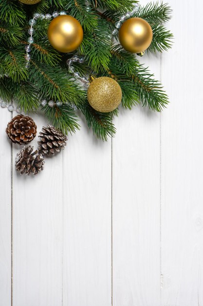 Branche d'arbre de Noël décorée de boules dorées et boîte-cadeau sur fond de bois blanc