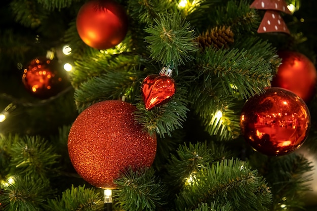 une branche d'un arbre de noël décorée de boules rouges avec des jouets