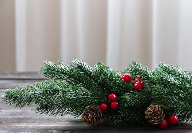 Branche d'arbre de Noël décorée de cônes de neige et de baies rouges sur une table en bois