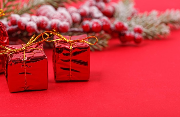 Branche d'arbre de Noël avec des jouets et un cadeau sur un gros plan de fond rouge